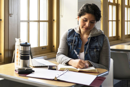 Young Hispanic woman studying near windows